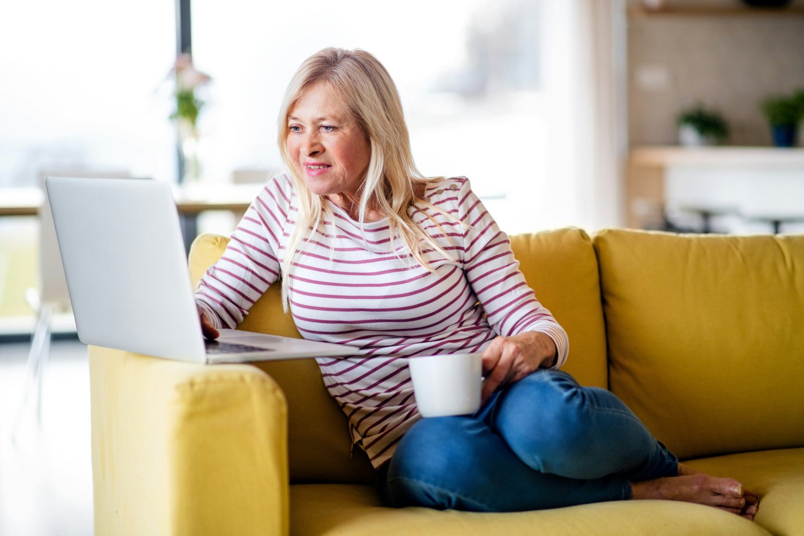 Woman on a yellow sofa calculating her savings in retirement